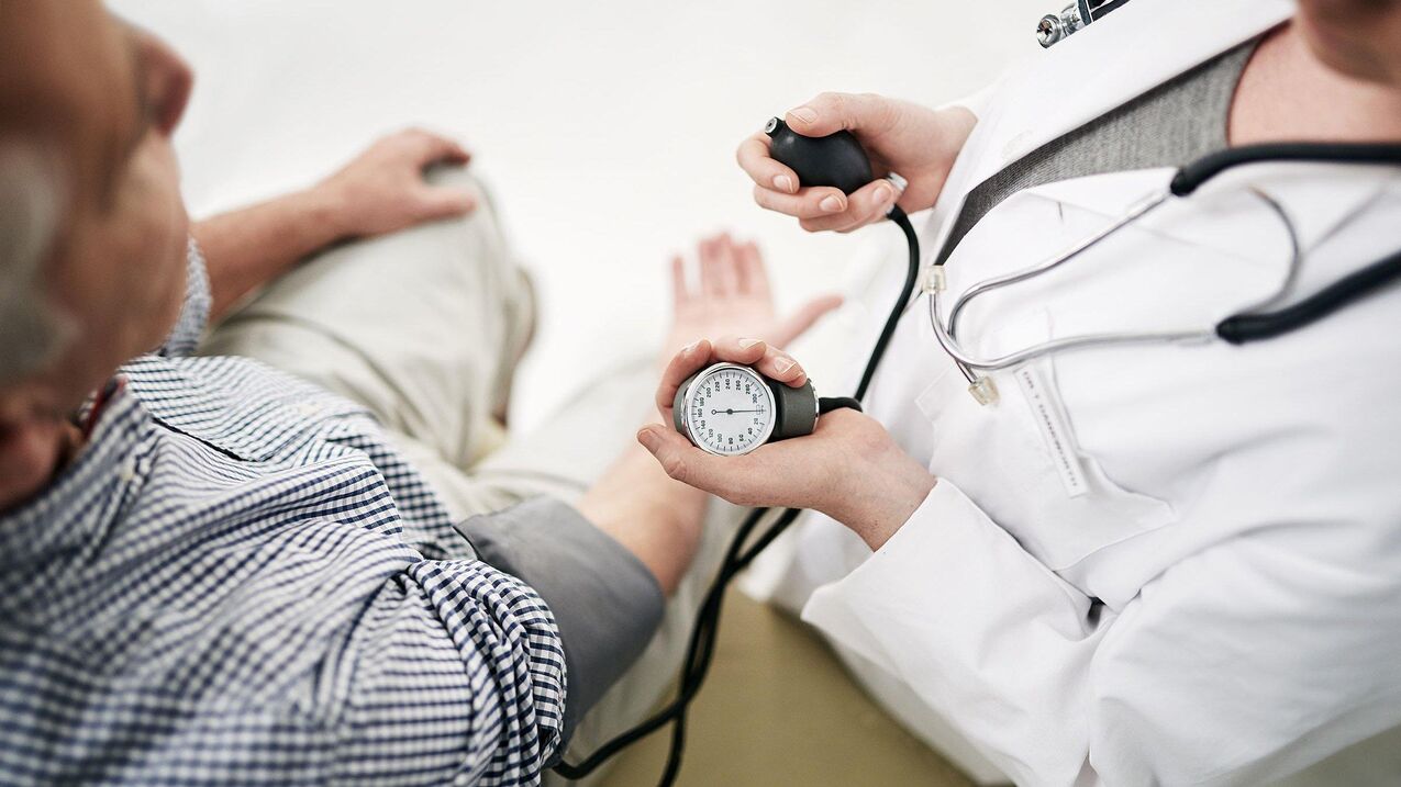 Cardiologist measures blood pressure of patient with symptoms of hypertension